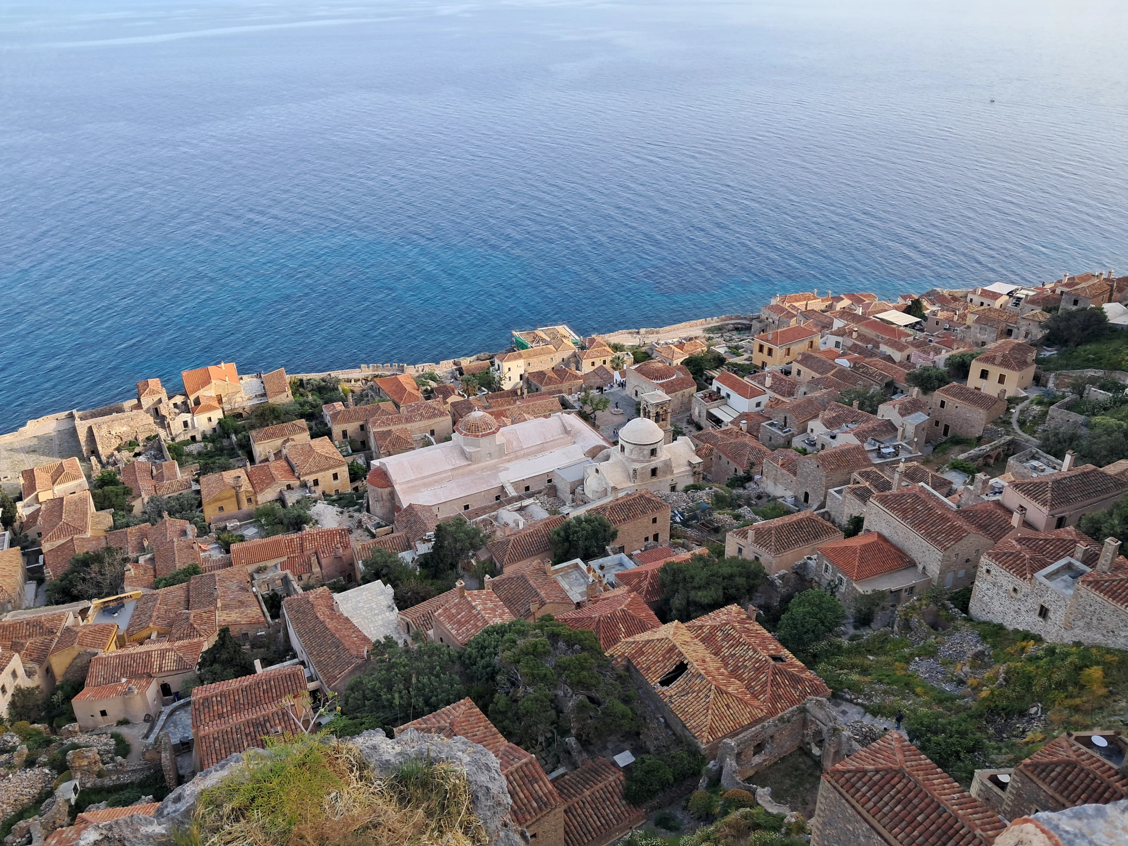 Historic coastal village with red-tiled roofs and blue sea.
