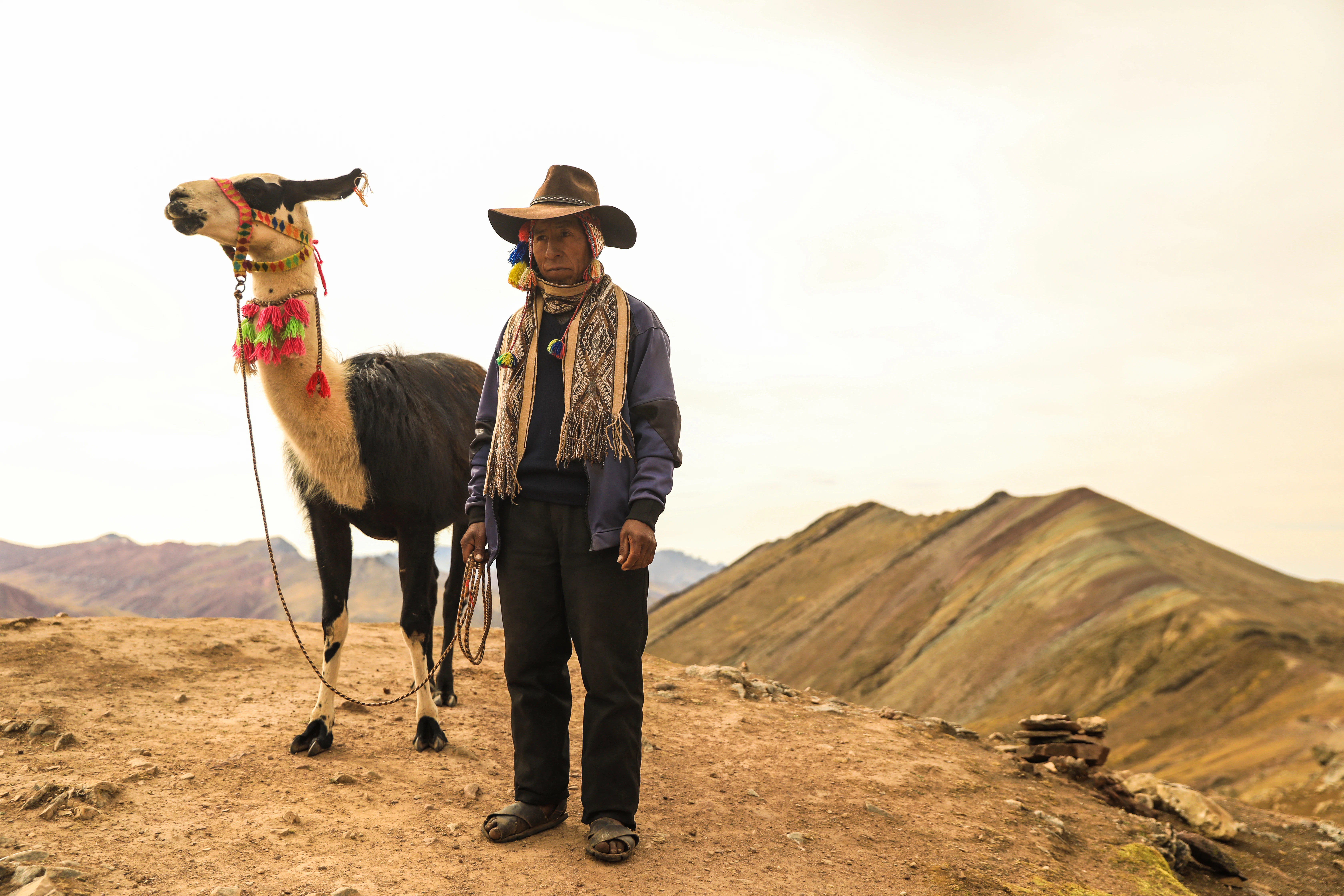 A man standing next to a camel on top of a mountain