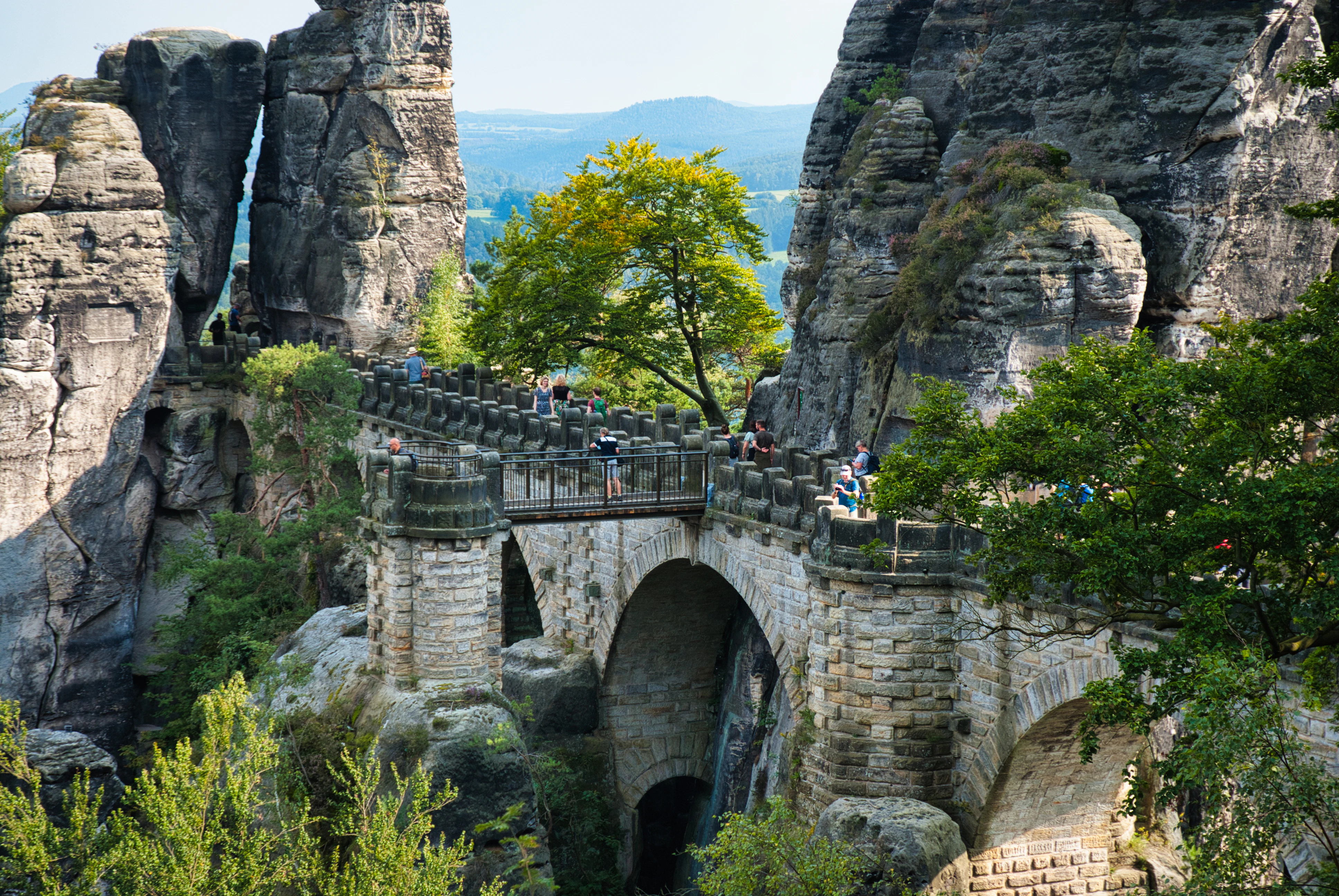 Stone bridge connecting rocky formations with lush greenery