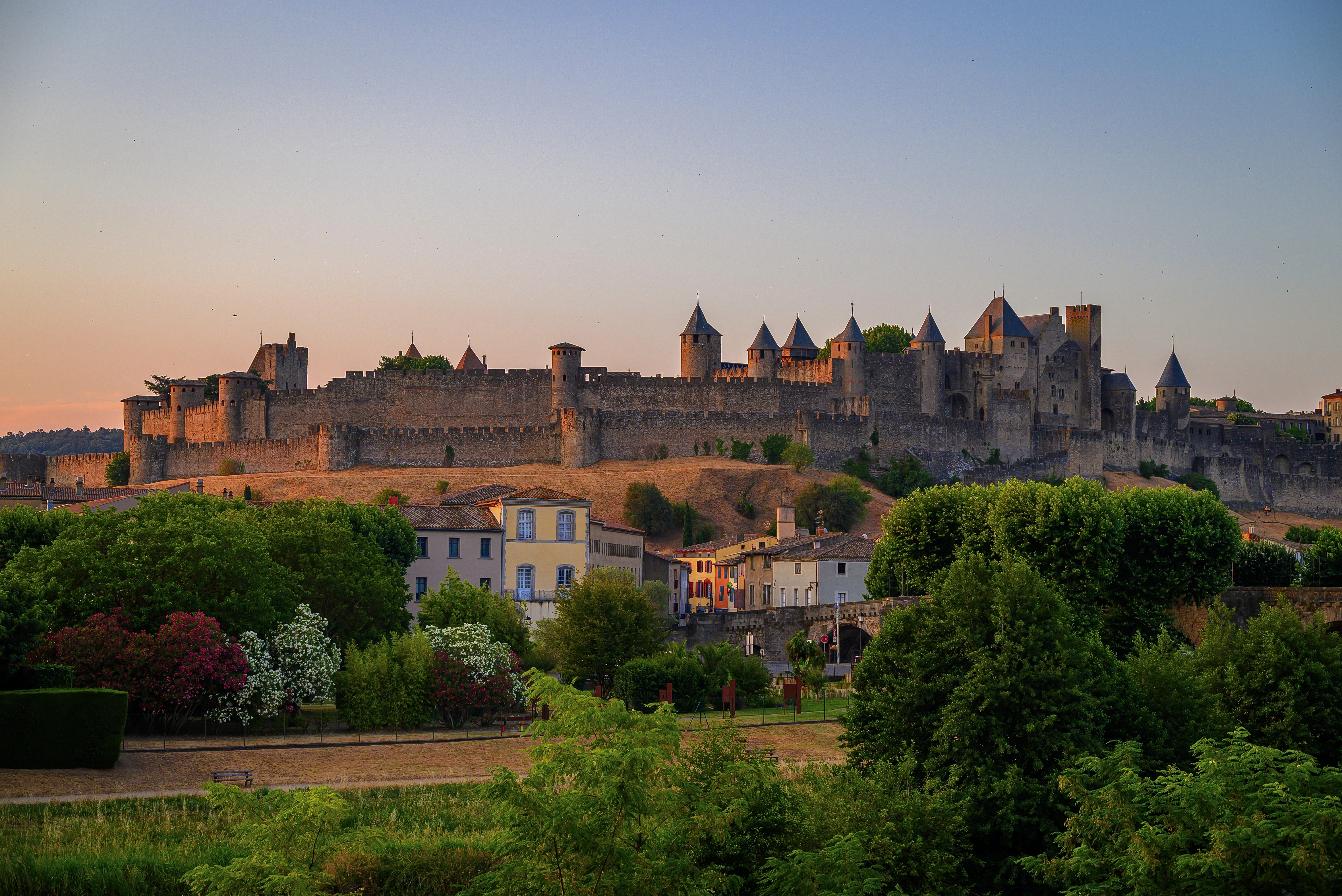 Medieval castle at sunset, surrounded by green foliage.