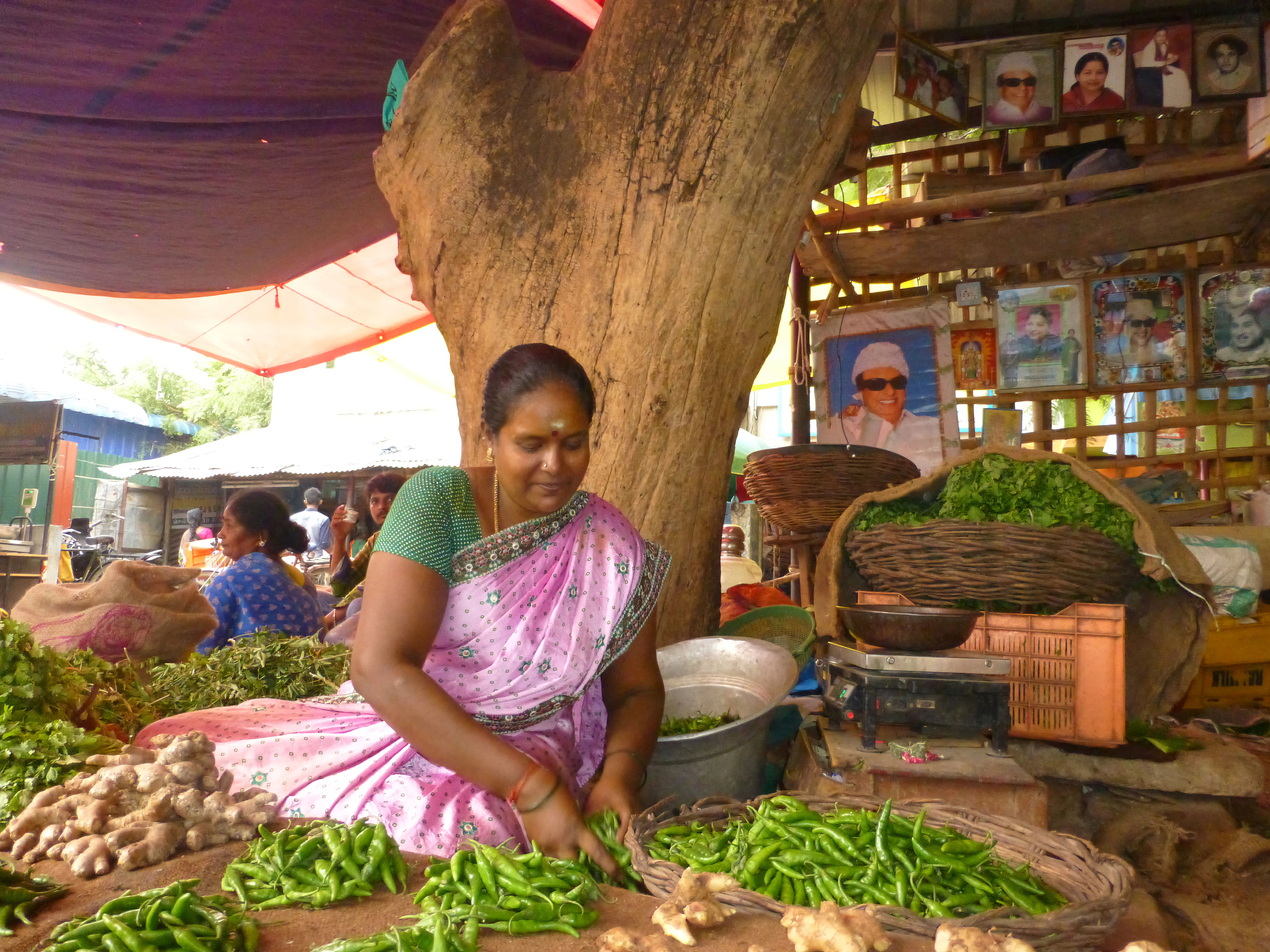 a woman sitting in front of a pile of vegetables