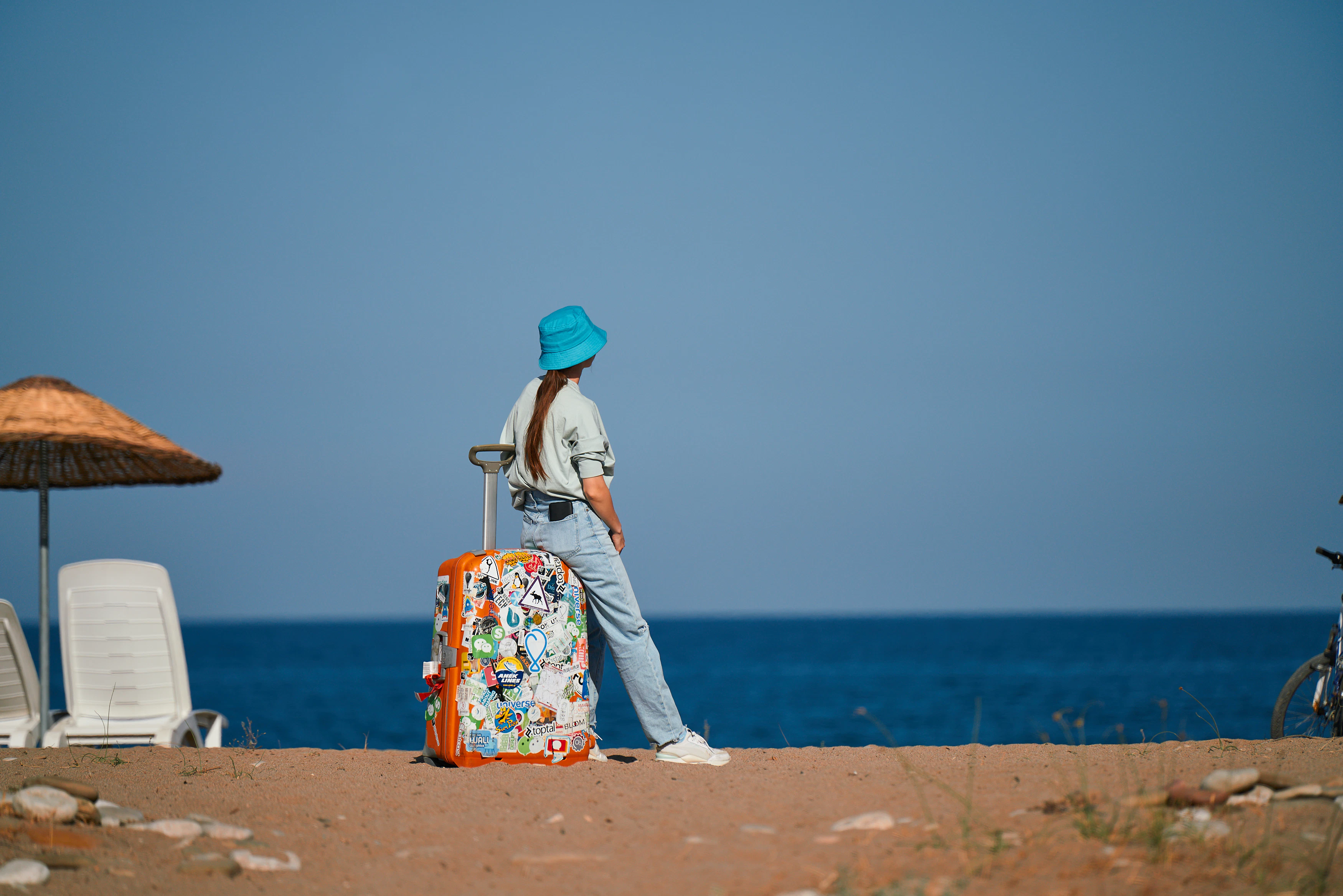 a woman standing on a beach with a suitcase