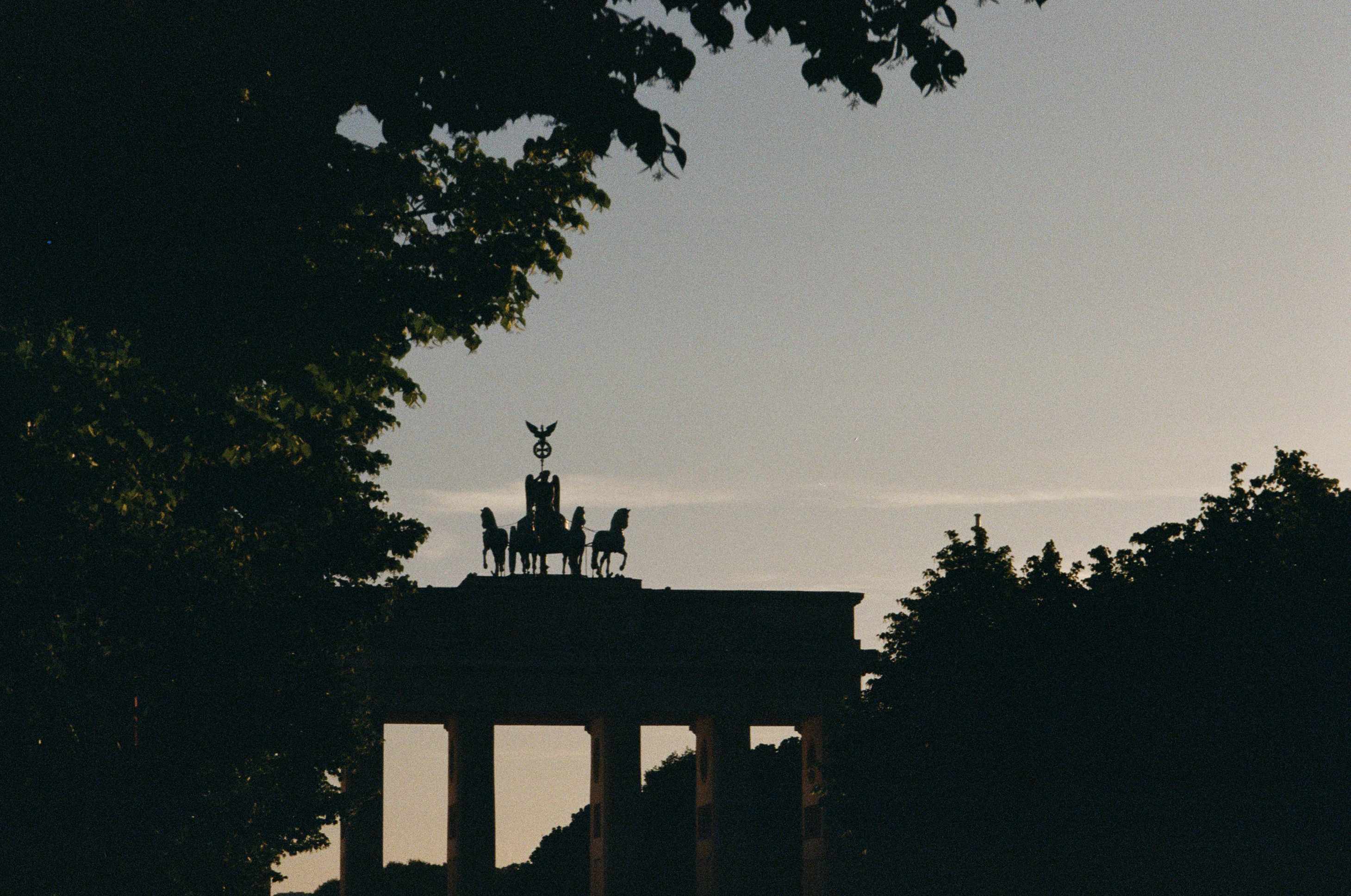 a silhouette of two people riding horses on top of a building