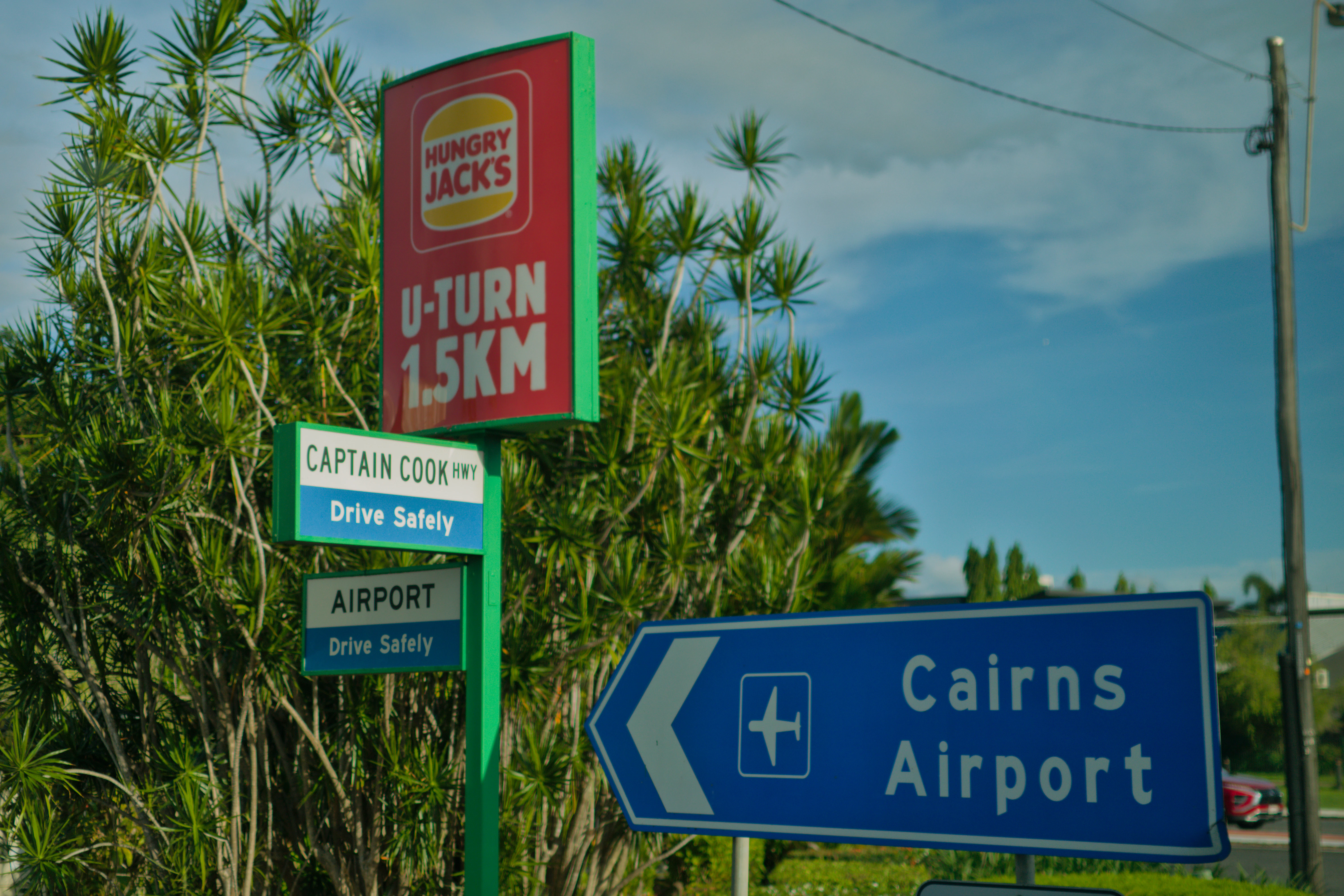Signs for hungry jacks, airport, and u-turn.