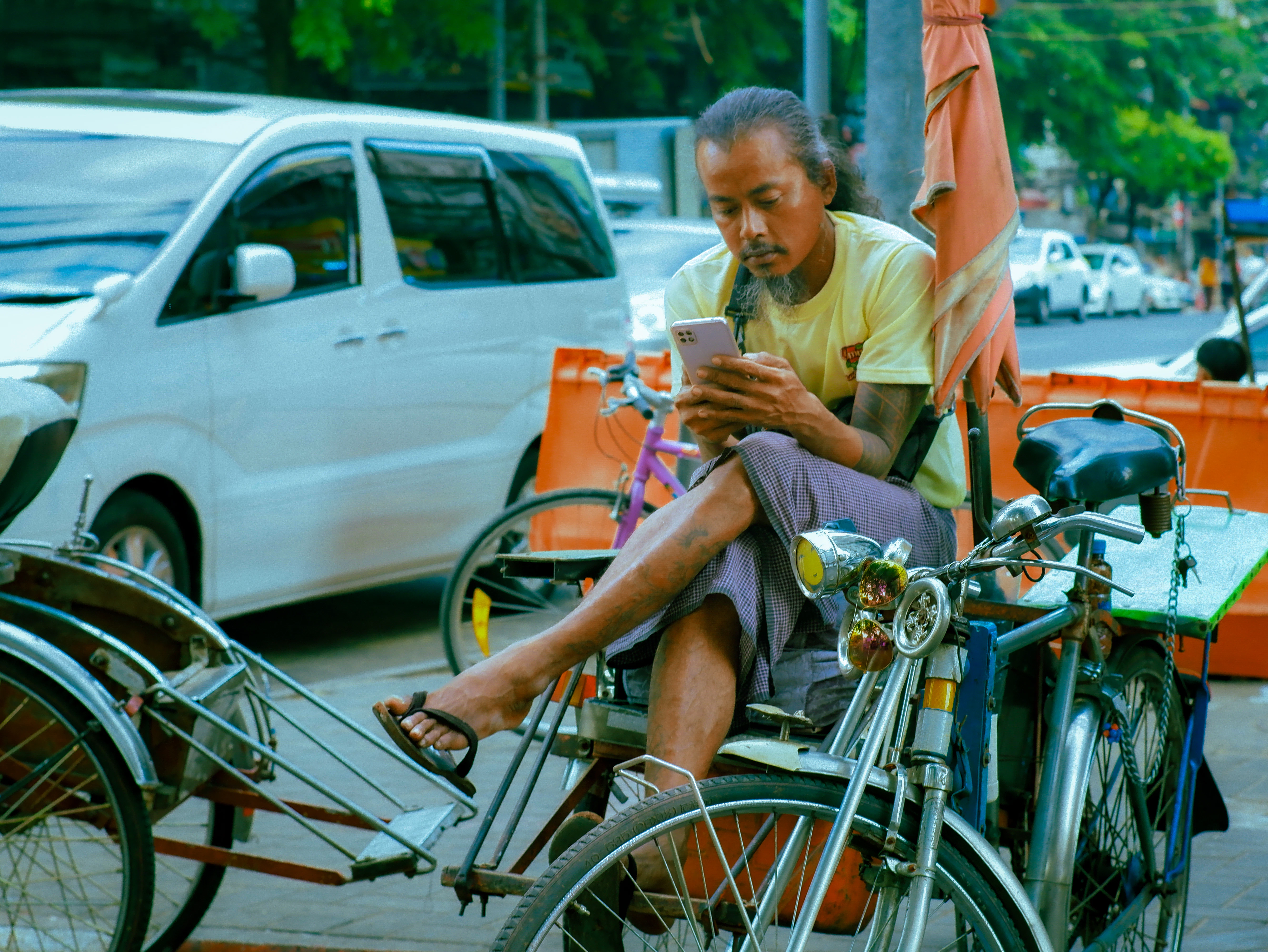 Man sitting in a rickshaw using his phone