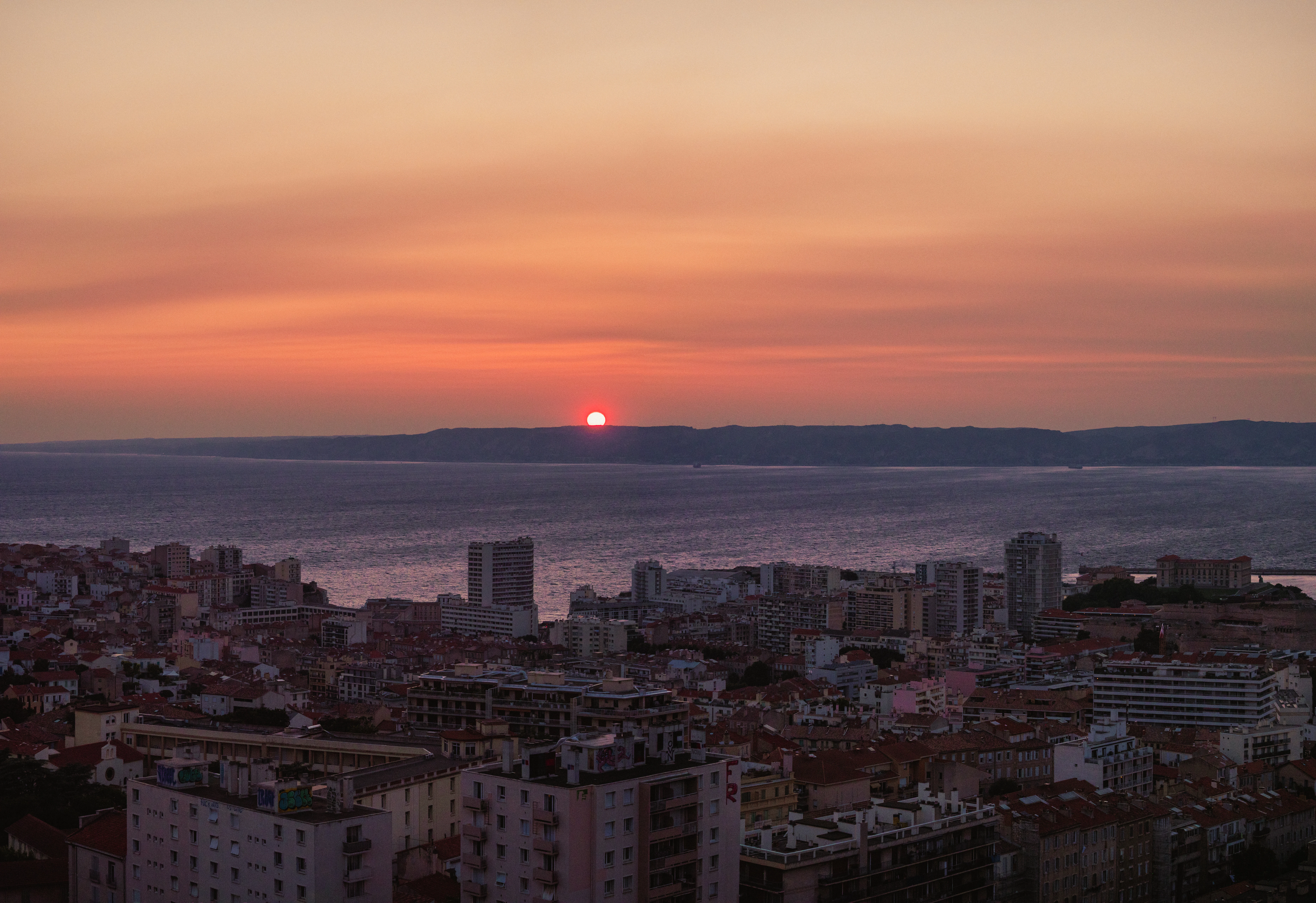 Sunset over a city with a body of water.